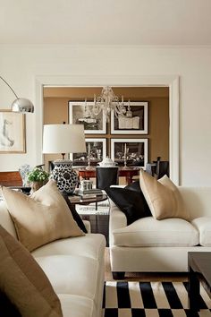 a living room filled with white furniture and lots of pictures on the wall above it