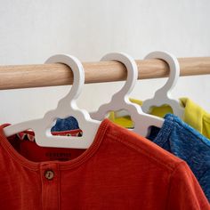 three shirts hanging on a clothes rack with wooden hangers