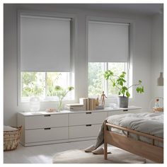 a bedroom with white walls and windows covered in blinds