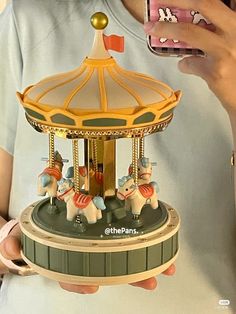 a person holding a cell phone in front of a carousel