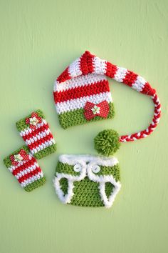 three crocheted hats and mittens on a green surface