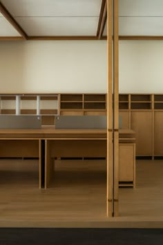 an empty room with tables and benches in the center, surrounded by wooden bookshelves