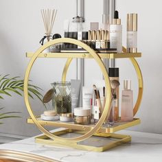 a gold circular shelf with cosmetics and other items on it in front of a white wall