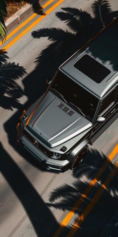 a car is parked on the side of the road with palm trees in the background