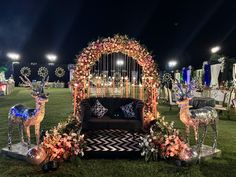 a decorated lawn area with deer statues and flowers on the grass, surrounded by lights