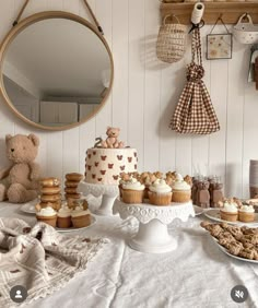 a table topped with lots of cakes and cupcakes next to a teddy bear