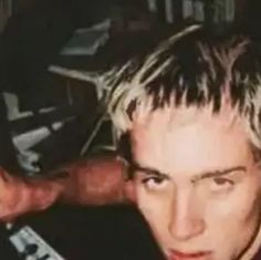 a young man with blonde hair is posing for the camera