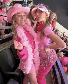 two girls dressed up in pink at a baseball game