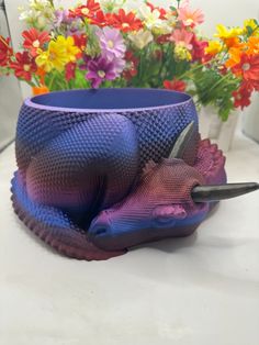 a purple vase sitting on top of a table next to colorful flowers and a pair of scissors