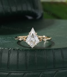 an engagement ring with a princess cut diamond on top, sitting on a green surface