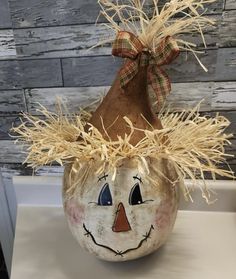 a pumpkin with a scarecrow face painted on it's side and hay in its mouth