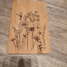 a wooden coaster with flowers and dragonflies on it