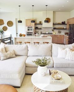 a living room filled with furniture next to a kitchen and dining room table in front of a white couch