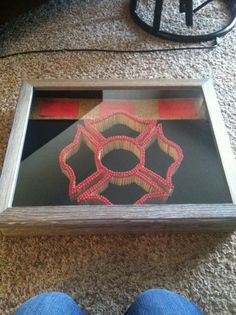 a person standing next to a framed object with red string on it's side