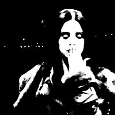 a black and white photo of a woman with her hand on her mouth in the dark