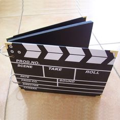 a black and white movie clapper sitting on top of a tile floor next to a wall