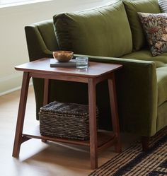 a green couch sitting next to a wooden table on top of a hard wood floor