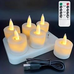 six lit candles with remote controls on the table next to each other and an electric charger