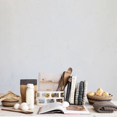 an open book sitting on top of a wooden table next to baskets and other items