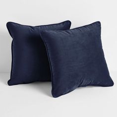 two dark blue pillows on a white surface