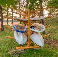 several surfboards are stacked on wooden boards in the grass near some trees and water