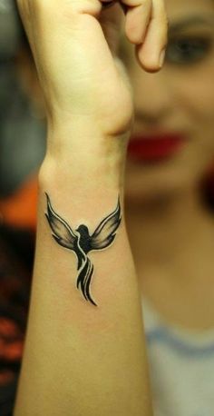 a woman's arm with a bird tattoo on the left side of her wrist