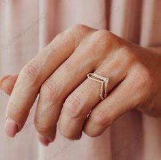 a woman's hand wearing a gold ring with two diamonds on the middle finger