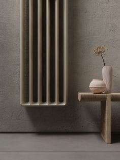 a white radiator sitting on top of a wooden table next to a vase