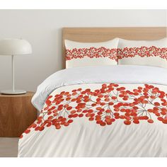 a bed with white and red comforters on top of it next to a lamp