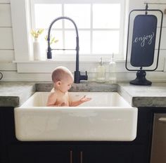 a baby sitting in a white kitchen sink