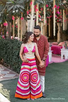 a man and woman standing next to each other in front of a tree filled with flowers