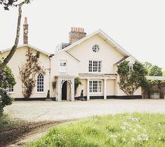 a large white house sitting on top of a lush green field