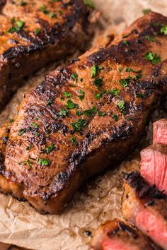 two pieces of steak sitting on top of a piece of paper next to some meat