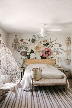 a bedroom with a hammock hanging from the ceiling and flowers on the wall