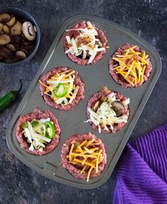 mini appetizers with cheese and vegetables on a baking tray next to a purple towel