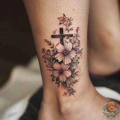 a cross with flowers on the side of her leg is shown in this tattoo design