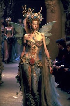 a woman dressed as a fairy with wings and flowers on her head is walking down the runway