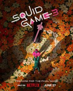 a person standing in front of a flower covered wall with the words squid game on it