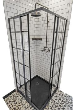 a walk in shower sitting next to a white tiled wall and floor with black grouting