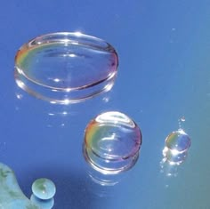 two soap bubbles floating on top of a blue surface