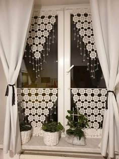 two potted plants sitting on top of a window sill in front of curtains