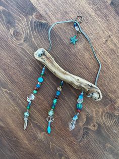 a piece of driftwood with beads and charms hanging from it on a wooden table