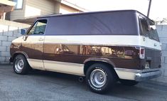 a brown and white van parked next to a brick wall