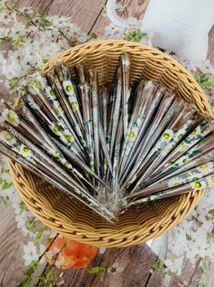 a basket filled with lots of silverware on top of a wooden table next to flowers