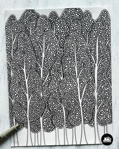 an ink drawing of trees with white and black lines on it, next to a marker