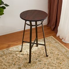 a wooden table sitting on top of a rug in front of a white curtained window