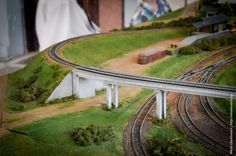 a model train track with two sets of tracks running along one side and an overpass on the other