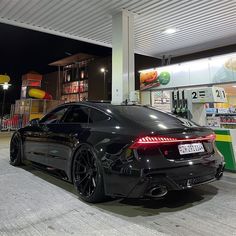 a black sports car parked in front of a gas station