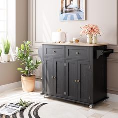 a room with a potted plant on top of it and a painting above the cabinet