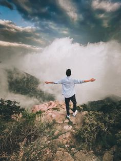 a man standing on top of a mountain with his arms outstretched